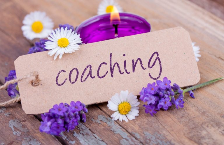 Lavendel, Gänseblümchen, kleiner violette Kerze und das Wort Coaching auf einem Zettel im Fokus